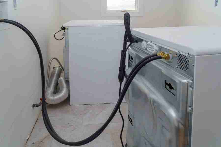 Washer and dryer pulled away from the wall showing supply hoses and connections in a Peoria AZ laundry room